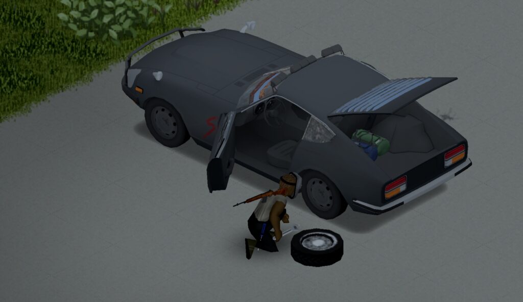 A grey sports car with its boot and front door open. A person kneels beside it changing a tyre.